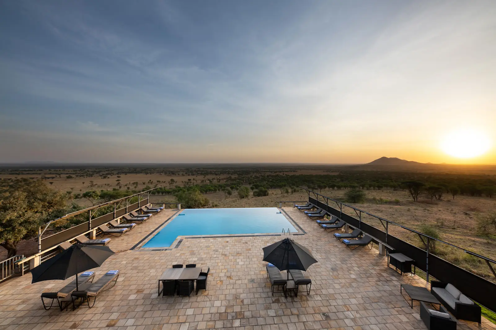 Swimming pool and loungers at sunset